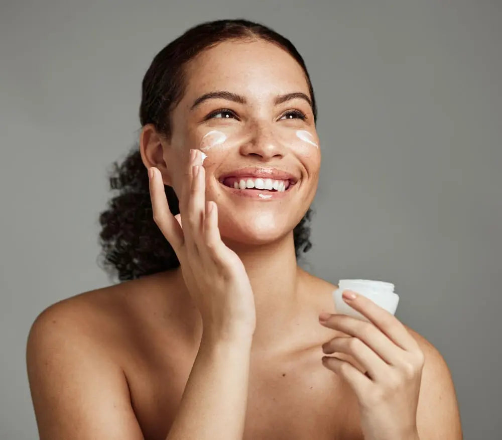 A woman putting cream on her face.